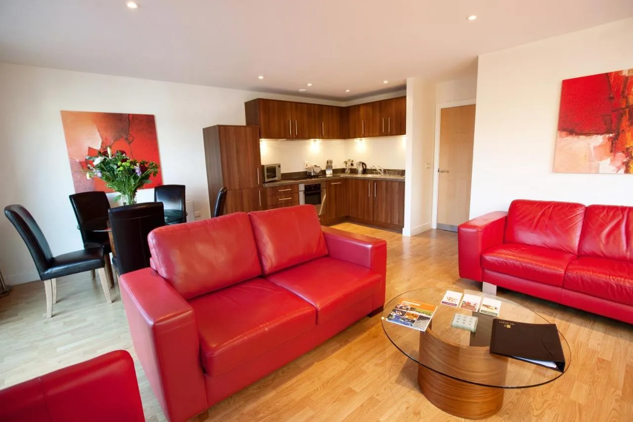 a living room with two red couches and a table at The Spires Serviced Apartments Birmingham in Birmingham